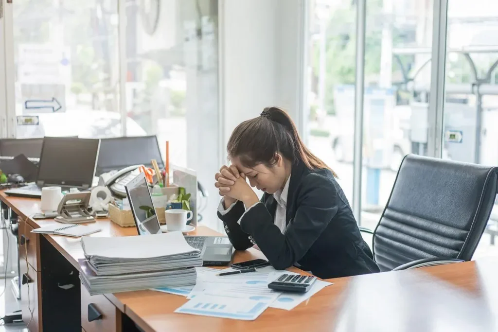 Stressed woman at a desk covered in paperwork