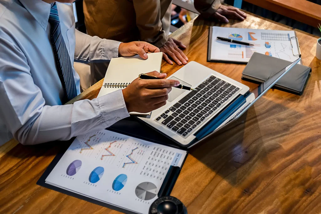 Team reviewing financial charts beside a laptop